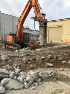 excavator using large hydraulic breaker to break up large concrete slabs at northrop grumman