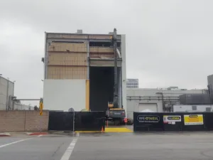 excavator demolishes metal exterior from a high-bay building at northrop grumman