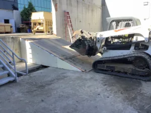 Skid steer with dozer blade about to drive up ramp at Vans Skatepark in Costa Mesa