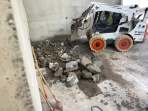 Bobcat using hydraulic breaker to fire its chisel point into the concrete at Vans Skatepark in Costa Mesa