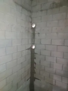 Two core holes drilled near the corner of a cinder block wall