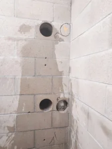 Close-up view of core holes drilled in a cinder block wall near a corner
