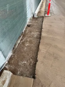 Cleanly cut section of concrete pavement removed along a construction fence line