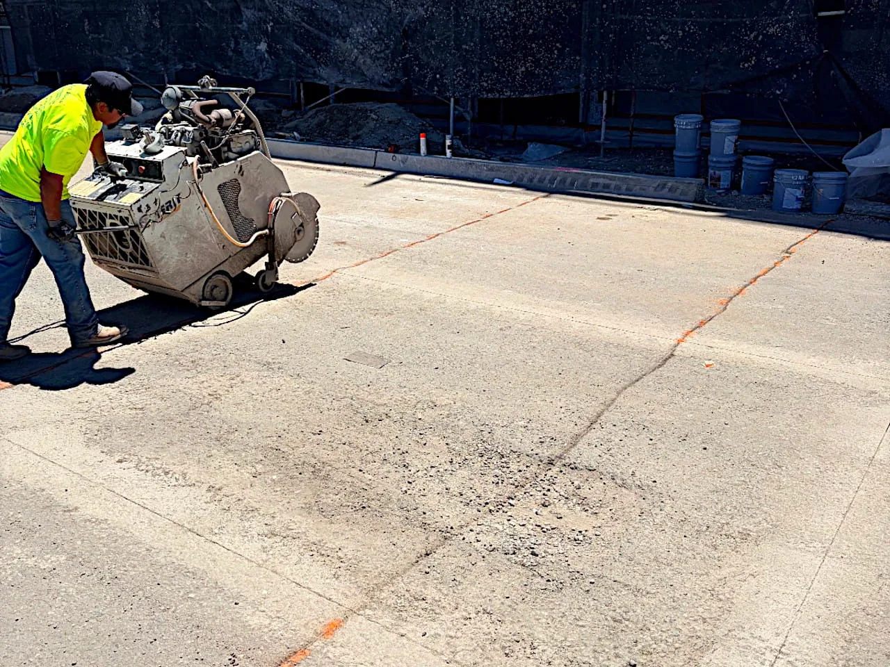 Intracut worker using a flat saw along marked lines on an outdoor concrete slab