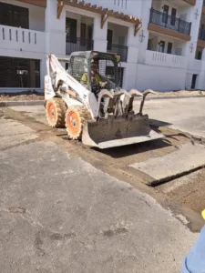 Bobcat loader equipped with a grapple bucket removing cut concrete slabs outdoors