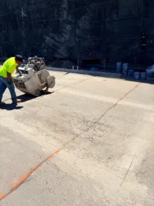 Intracut worker using a flat saw along marked lines on an outdoor concrete slab
